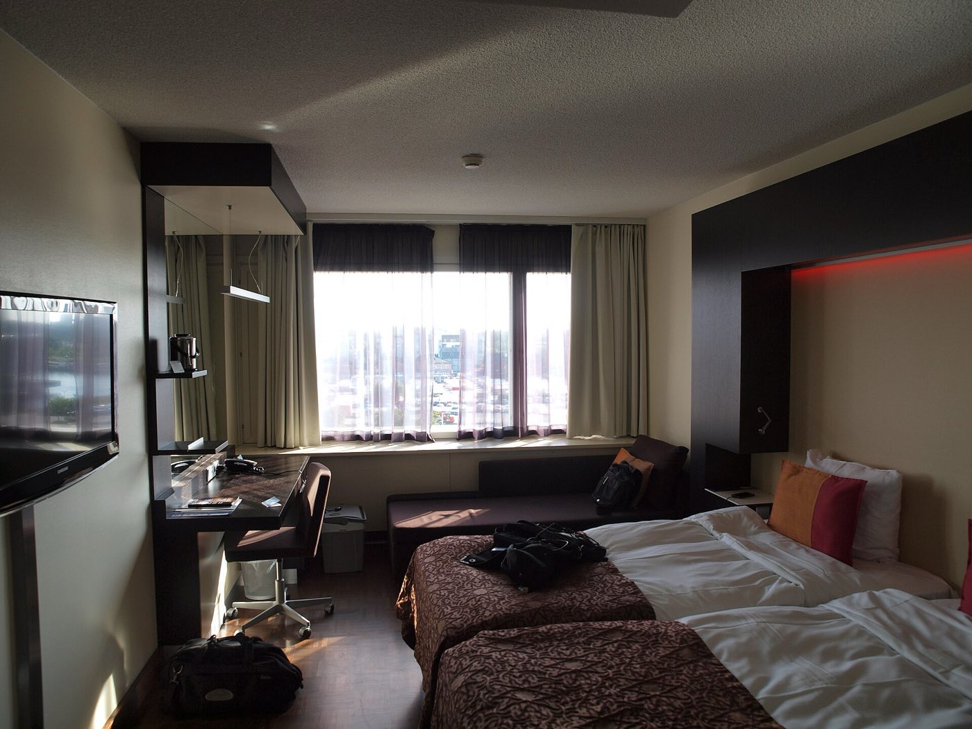 Contemporary hotel room with a large bed, desk and floor-to-ceiling window