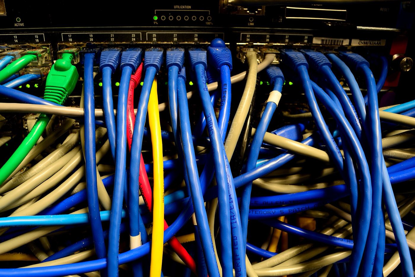 Network switch with rows of blue, green and yellow patch cables connected