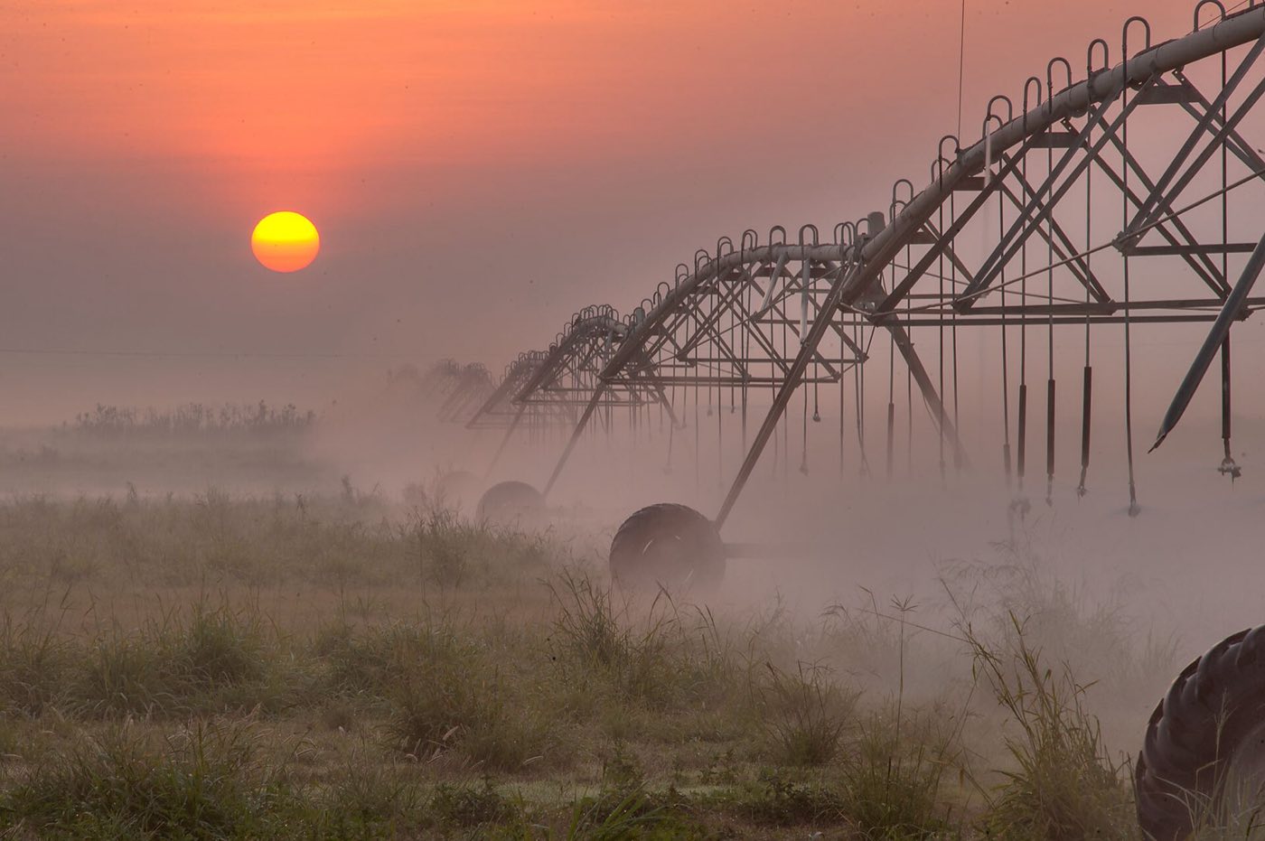 Centre-pivot irrigation over farmland at sunrise